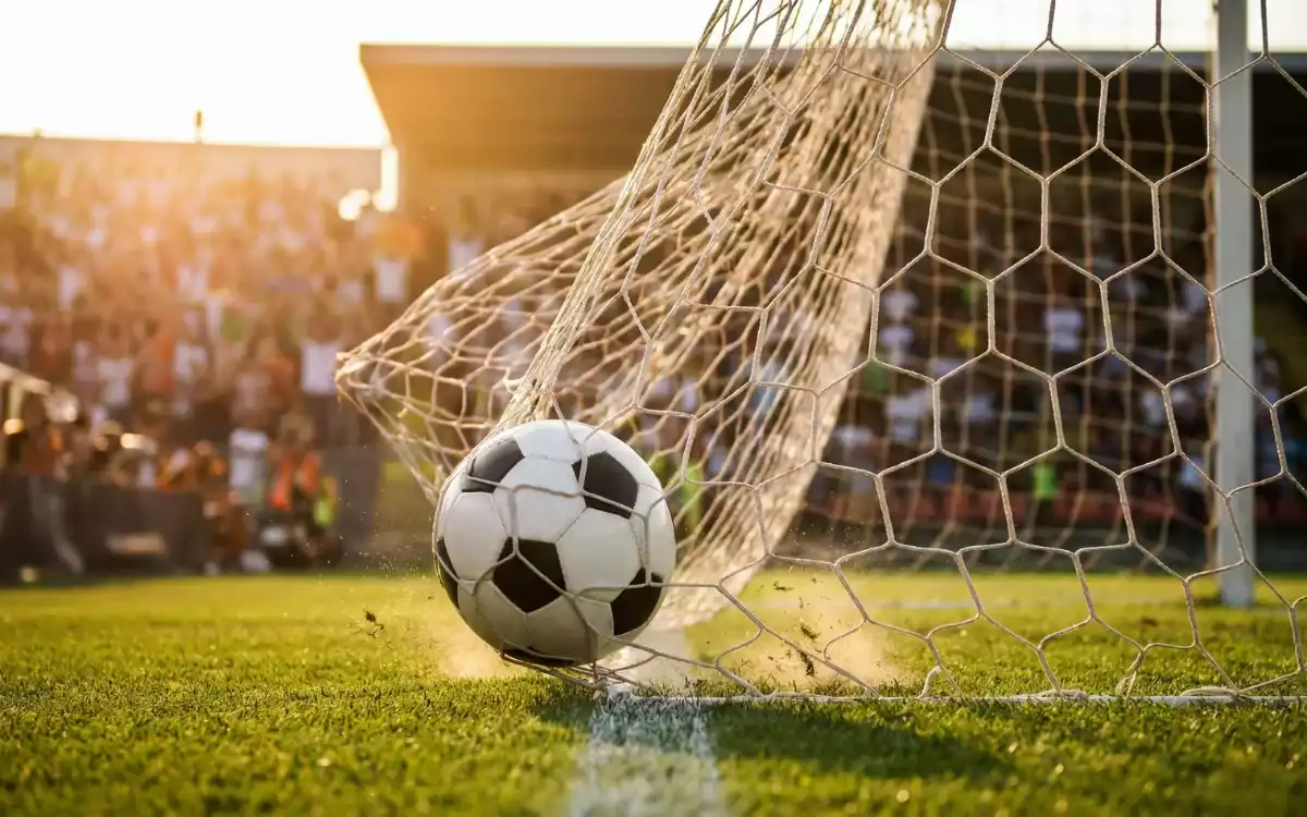 Portería de fútbol con balón entrando en la red durante un partido